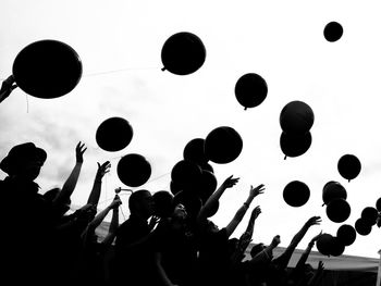 Low angle view of silhouette people playing against sky