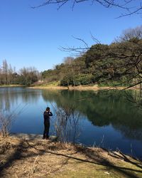 Rear view of man overlooking calm lake