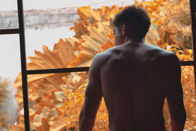 Rear view of man standing against wall during autumn