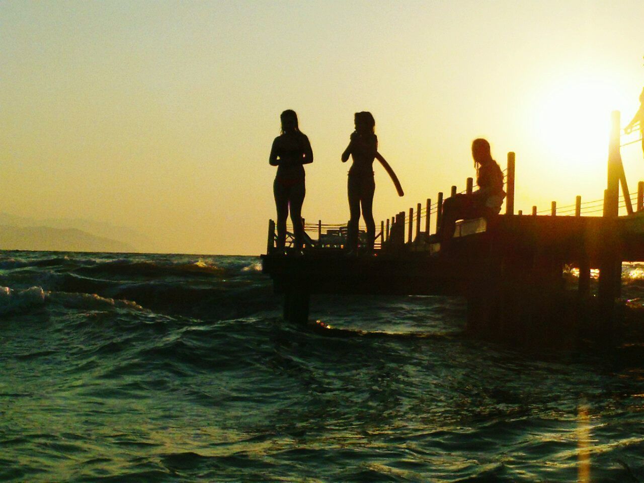 sunset, water, silhouette, sea, men, leisure activity, lifestyles, sun, clear sky, waterfront, copy space, orange color, person, horizon over water, scenics, standing, nature, sky