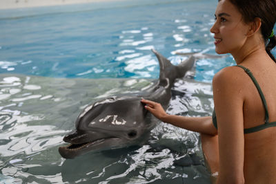 Woman with dolphin sitting in swimming pool