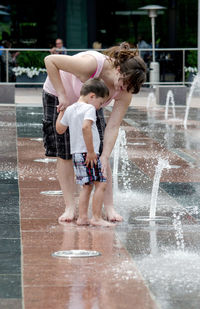 Mom and son happily play in an urban splash pad