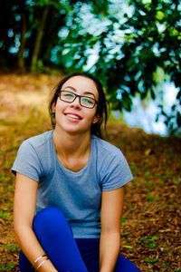 Portrait of smiling young woman sitting on field in park