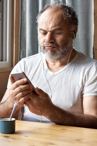 Mid adult man sitting on table at home