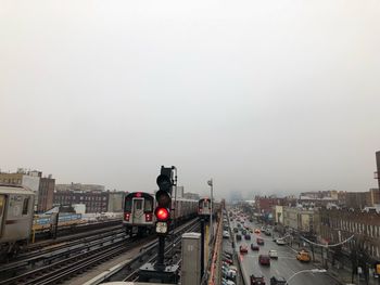 Cars on railroad track in city against clear sky