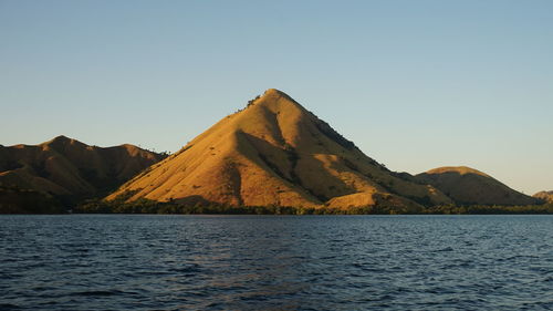 Scenic view of lake by mountain against clear sky