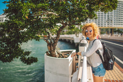 Portrait of smiling young woman standing against trees