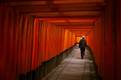 Rear view of man walking in corridor of building