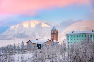 Houses on snowcapped mountain against sky during winter