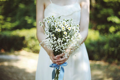 Midsection of woman holding white flower