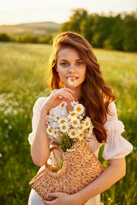 Portrait of smiling young woman sitting on field