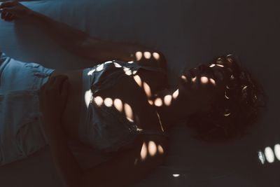 High angle view of woman lying on bed in darkroom