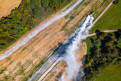 Aerial view of a tractor spreading lime on fields to improve soil quality after the harvest. 