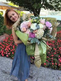 Portrait of smiling woman standing by flower bouquet