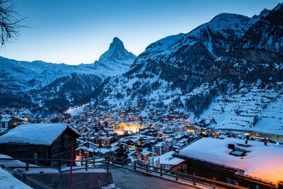 Snow covered townscape by mountain against sky