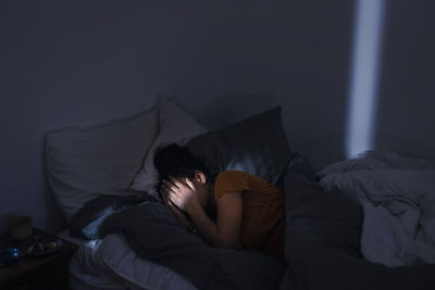 Crying young woman lying in bed