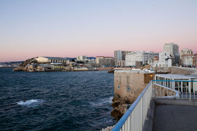 Buildings by sea against clear sky