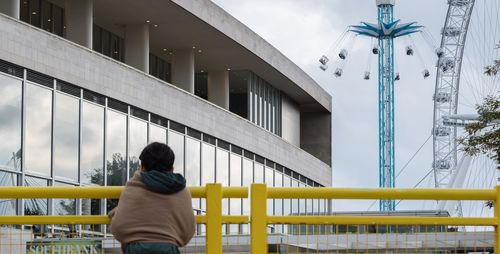 Rear view of man standing by railing in city