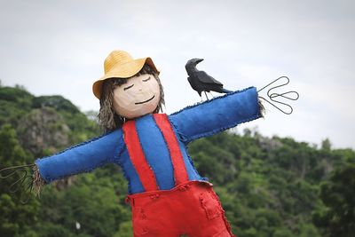 Scarecrow by mountain against sky
