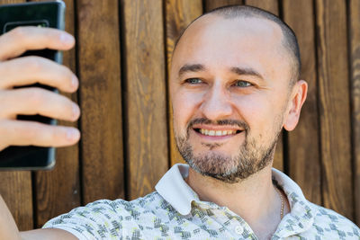 Portrait of smiling young man standing against wall