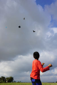 Rear view of boy flying against sky