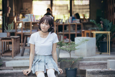 Young woman looking away while sitting outdoors