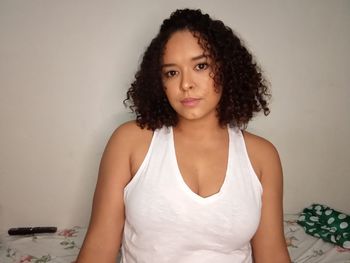 Portrait of beautiful woman standing against wall at home