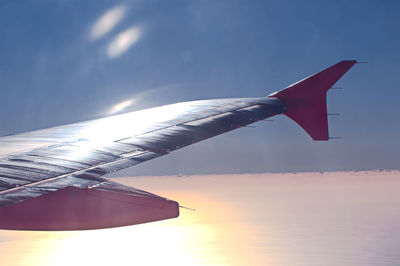 Low angle view of airplane flying against sky during sunset