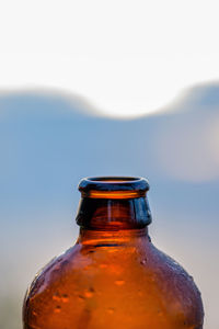 Close-up of wet bottle against sky