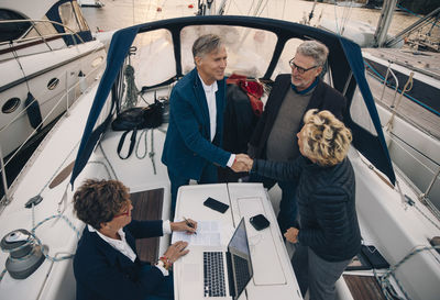 High angle view of senior male and female friends greeting in yacht