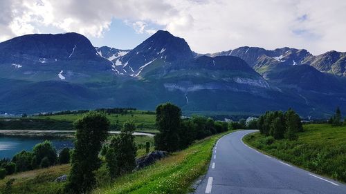 Road by mountains against sky