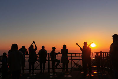 Silhouette people against orange sky