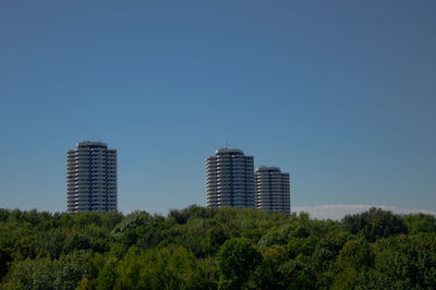 Trees and buildings against clear blue sky