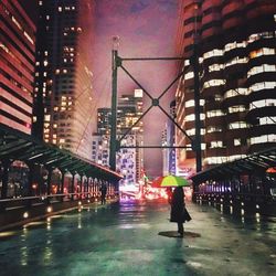 Woman standing on illuminated city street at night