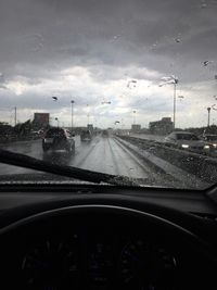 Cars on road seen through wet windshield of car