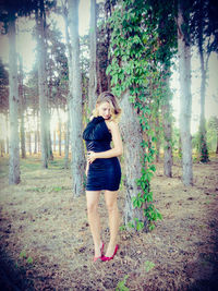 Full length of young woman standing in forest