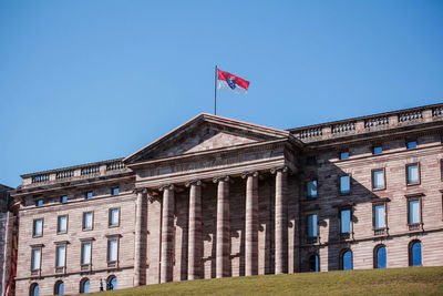 Low angle view of flags against clear blue sky