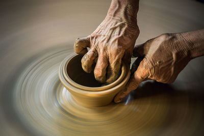 Cropped hands of man making pottery in workshop