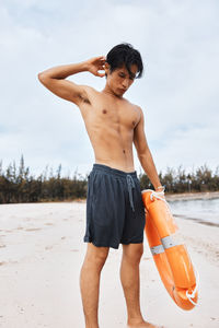 Shirtless man standing at beach