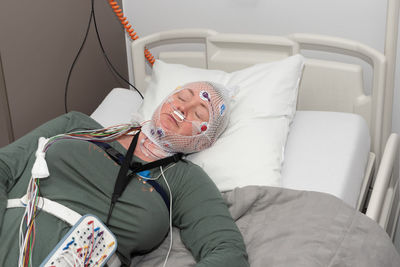Middle aged woman measuring brain waves, examining polysomnography in sleep lab