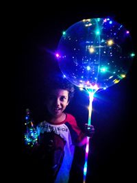 Portrait of smiling woman holding illuminated lights at night