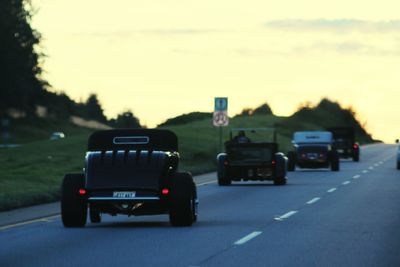 Cars on road against sky during sunset