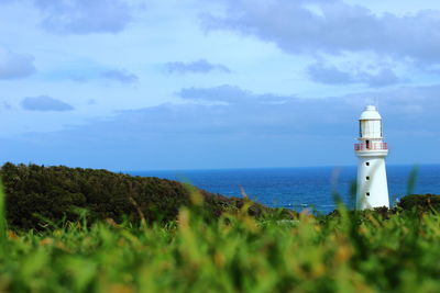 Lighthouse by sea against sky