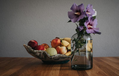Close-up of fresh fruits in vase on table against wall