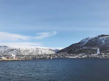 Scenic view of sea by snowcapped mountains against sky
