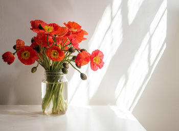 Close-up of red flower vase on table against wall