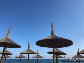 Traditional windmill on beach against clear blue sky