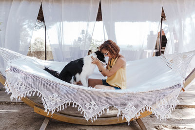 Rear view of woman with dog sitting on floor