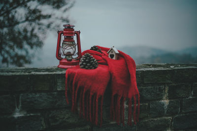 Still life of red lantern, red scarf and pinecones on a stone wall