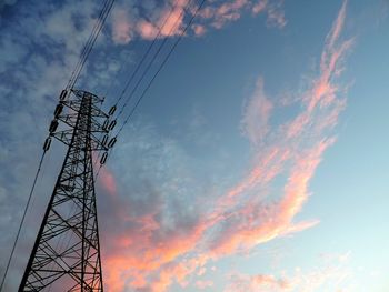 Low angle view of electricity pylon against cloudy sky